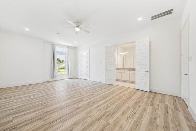 interior space with connected bathroom, ceiling fan, and light hardwood / wood-style flooring