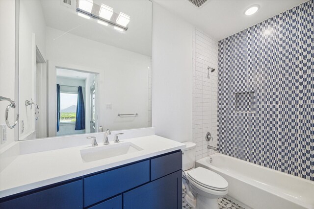 full bathroom with tiled shower / bath combo, vanity, and toilet