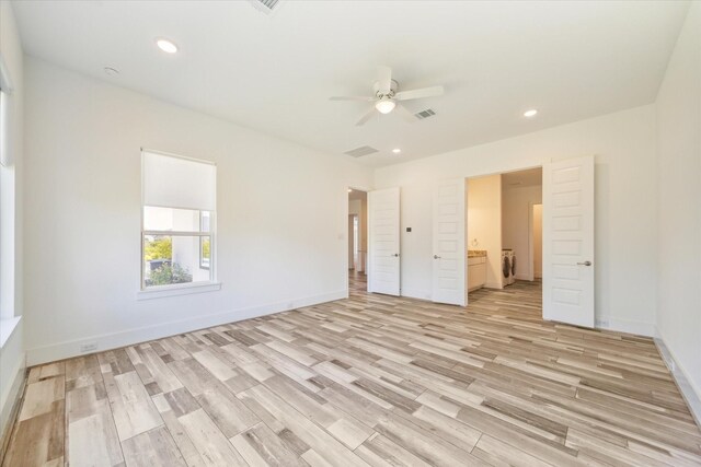 unfurnished bedroom featuring ensuite bathroom, ceiling fan, independent washer and dryer, and light hardwood / wood-style flooring