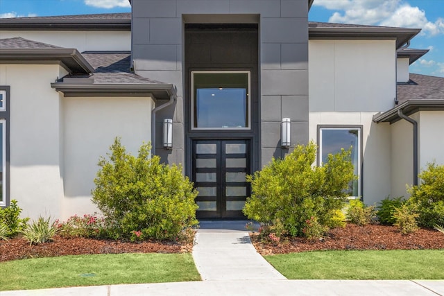 property entrance featuring stucco siding and a shingled roof