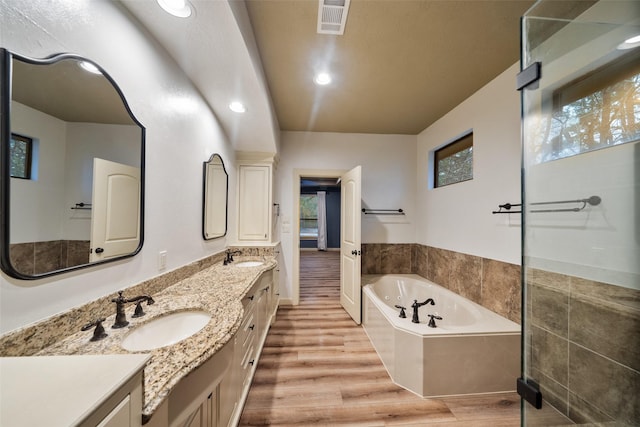 bathroom featuring vanity, a relaxing tiled tub, and wood-type flooring