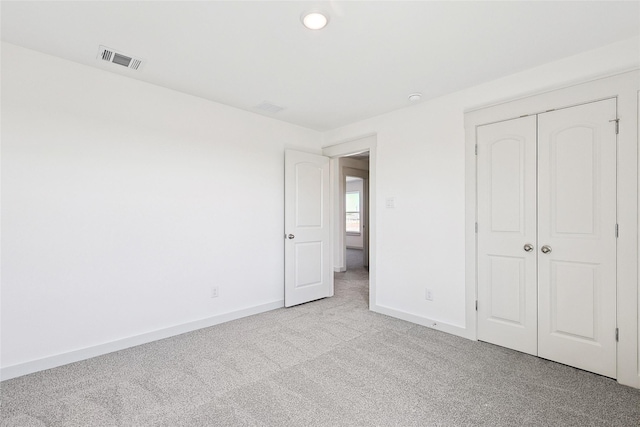 unfurnished bedroom featuring light colored carpet and a closet