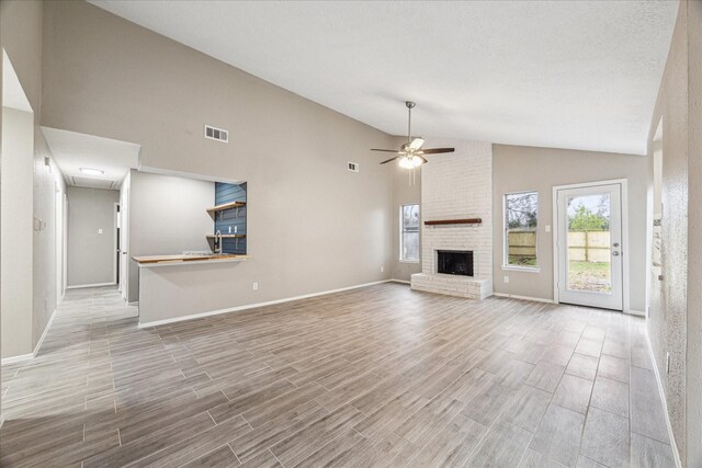 unfurnished living room featuring ceiling fan, a fireplace, vaulted ceiling, and a textured ceiling