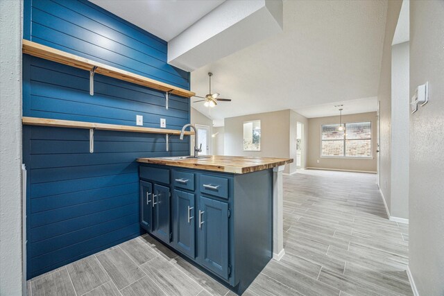 kitchen with pendant lighting, sink, ceiling fan, butcher block counters, and blue cabinets