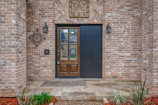 doorway to property featuring brick siding