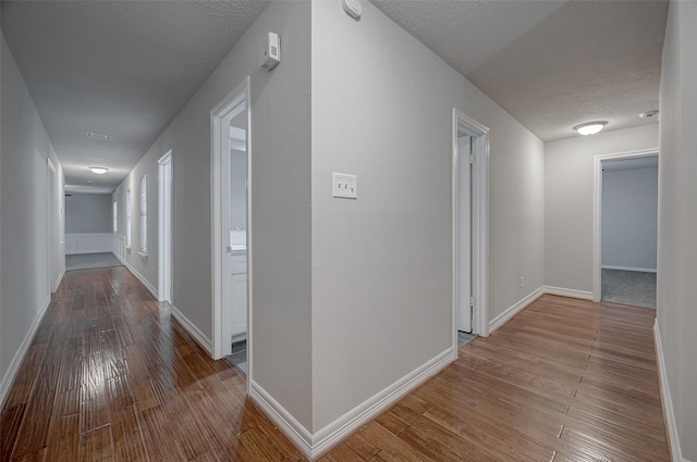 corridor with hardwood / wood-style flooring and a textured ceiling