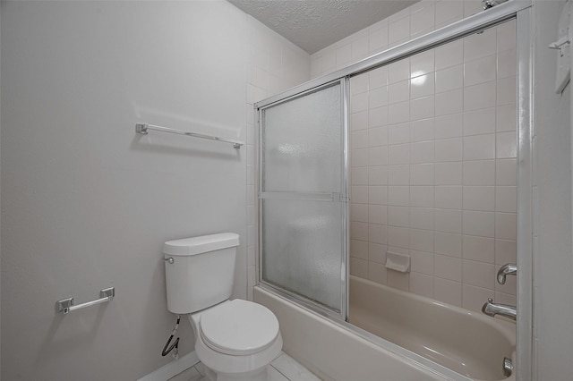 bathroom with bath / shower combo with glass door, toilet, and a textured ceiling