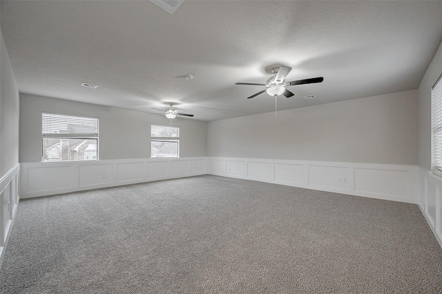 empty room with ceiling fan, carpet flooring, and a textured ceiling