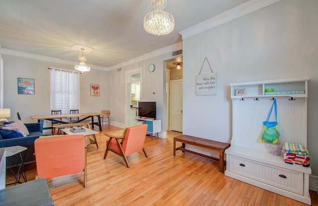 living room with a notable chandelier, light hardwood / wood-style flooring, and ornamental molding