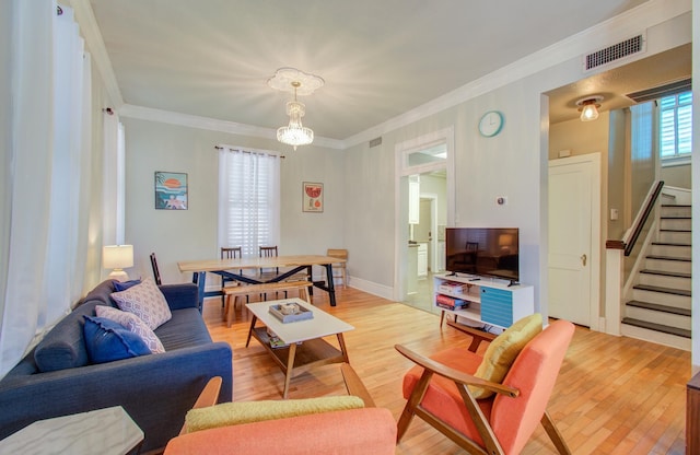 living room with crown molding, an inviting chandelier, and light hardwood / wood-style flooring