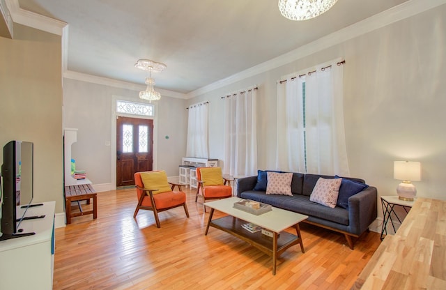 living room with crown molding, a chandelier, and light hardwood / wood-style flooring