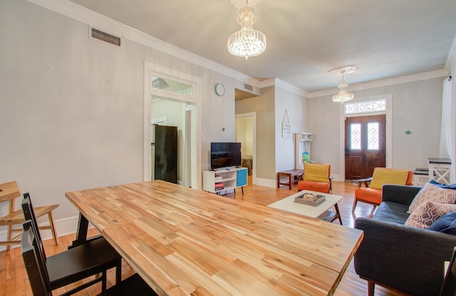 dining room featuring a notable chandelier, ornamental molding, and light hardwood / wood-style floors