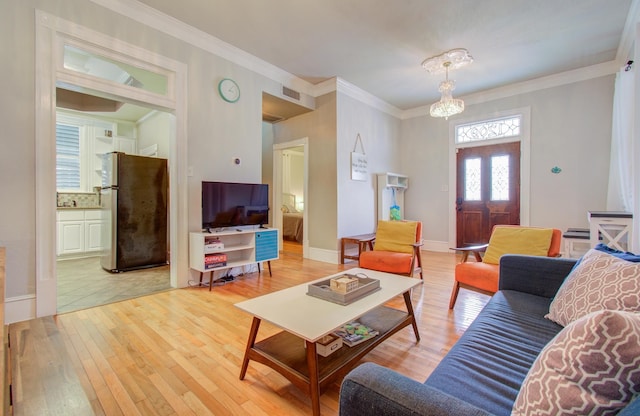 living room with an inviting chandelier, light hardwood / wood-style flooring, and ornamental molding