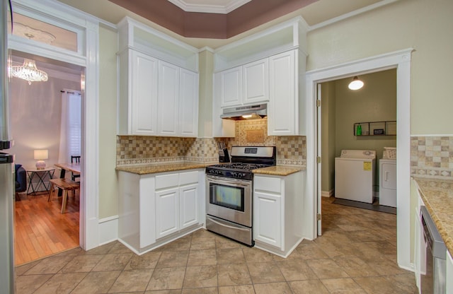 1209 Rosenberg St, Galveston, TX 77550 - kitchen with stainless steel gas stove, washer and dryer, under cabinet range hood, white cabinetry, and crown molding