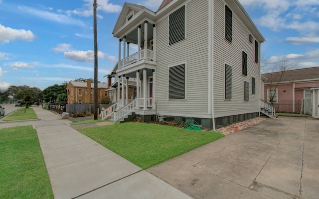 view of side of home with a lawn and a balcony