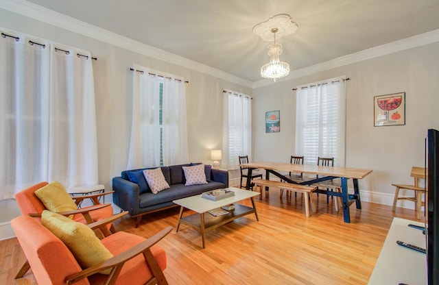 living room with crown molding, a chandelier, and light wood-type flooring