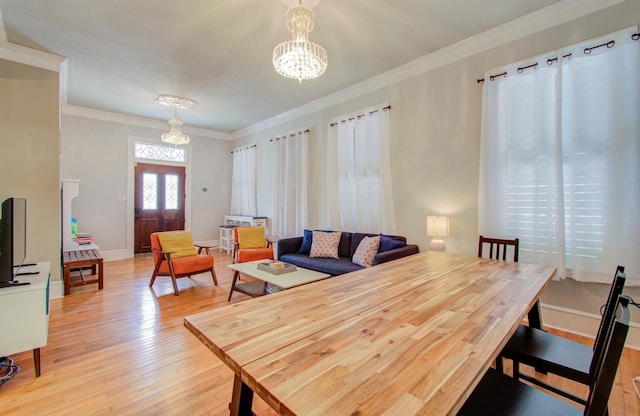 dining area with ornamental molding, a chandelier, and light hardwood / wood-style flooring