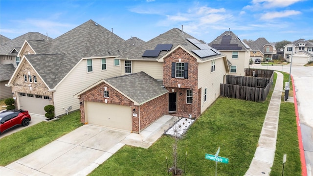 traditional-style house with brick siding, roof mounted solar panels, a shingled roof, concrete driveway, and a residential view