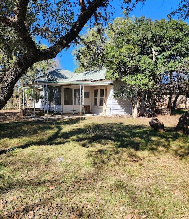 back of house with a sunroom and a lawn