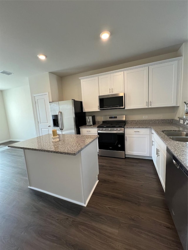 kitchen featuring appliances with stainless steel finishes, sink, white cabinets, dark hardwood / wood-style flooring, and a center island