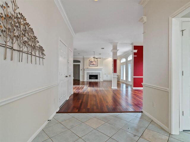 unfurnished living room with light tile patterned floors, a fireplace, ornamental molding, and decorative columns