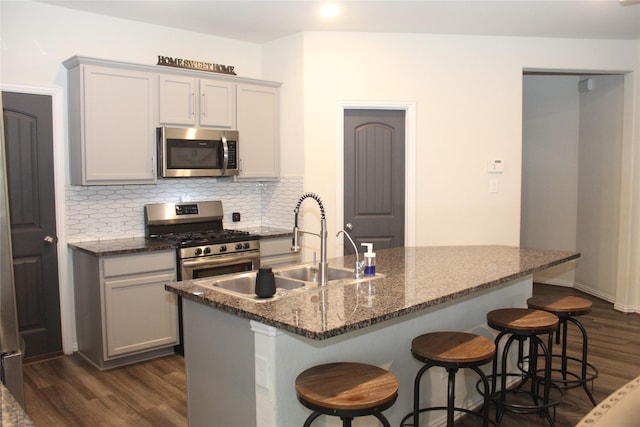 kitchen with a sink, stainless steel appliances, dark wood-type flooring, and backsplash