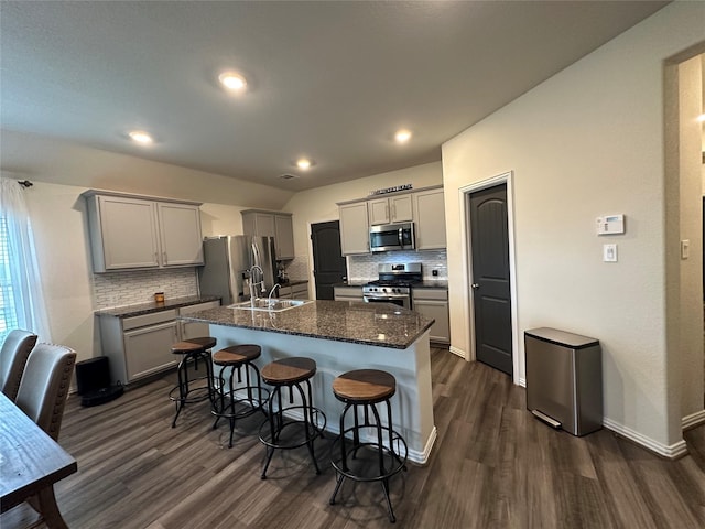 kitchen with appliances with stainless steel finishes, a breakfast bar, sink, gray cabinetry, and a kitchen island with sink