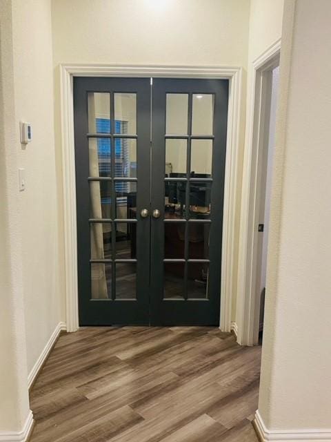 doorway with french doors, baseboards, and wood finished floors