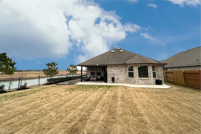 rear view of house with a patio, a fenced backyard, brick siding, a water view, and a yard