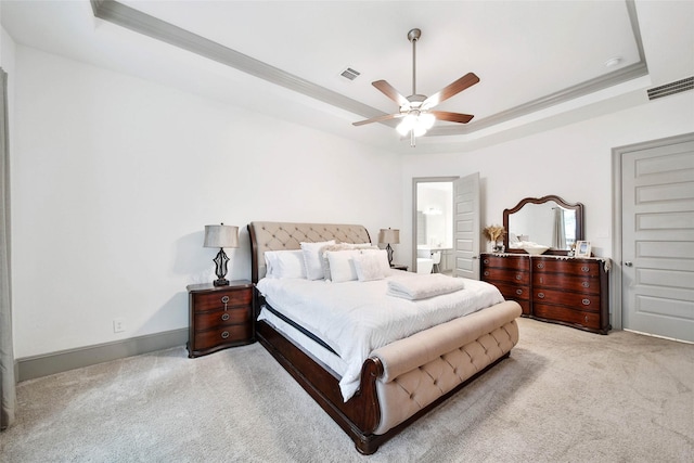 carpeted bedroom with ornamental molding, connected bathroom, ceiling fan, and a tray ceiling