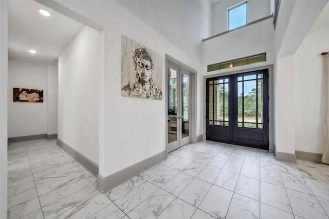 foyer entrance with french doors and a towering ceiling