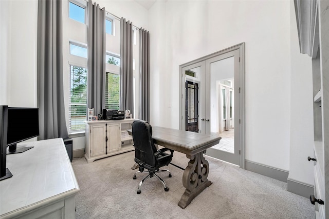 office with french doors, light carpet, and a high ceiling