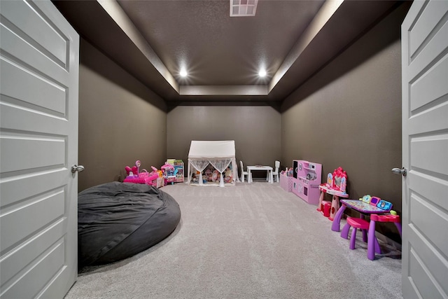 game room featuring light carpet, a tray ceiling, and a textured ceiling