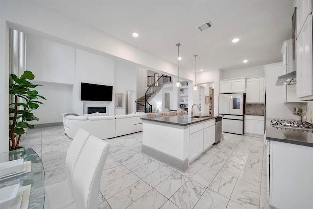 kitchen featuring white cabinetry, hanging light fixtures, a kitchen island with sink, and stainless steel appliances