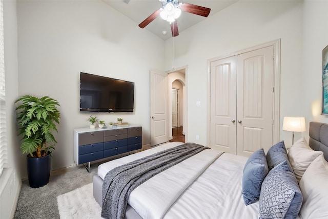 bedroom with vaulted ceiling, light colored carpet, a closet, and ceiling fan