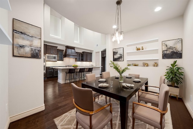 dining area with dark wood-type flooring and an inviting chandelier