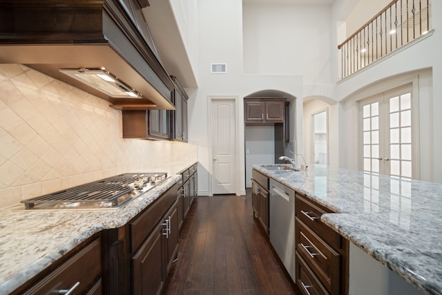 kitchen featuring stainless steel appliances, light stone countertops, sink, and dark wood-type flooring