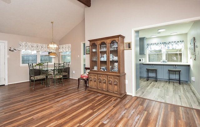 dining space featuring baseboards, high vaulted ceiling, and wood finished floors