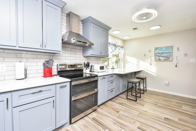 kitchen with visible vents, decorative backsplash, white microwave, wall chimney range hood, and double oven range