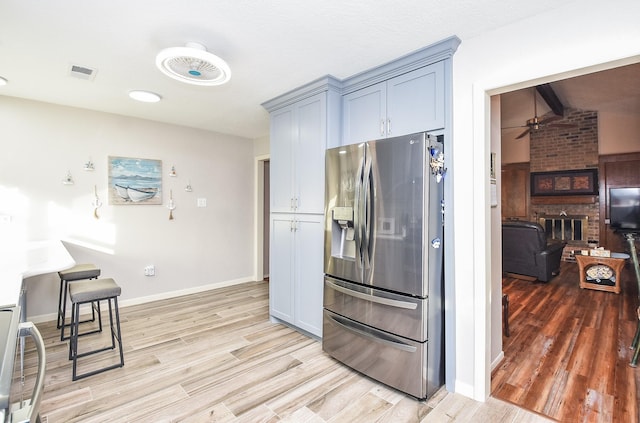 kitchen featuring visible vents, light wood-style flooring, stainless steel fridge, range, and baseboards