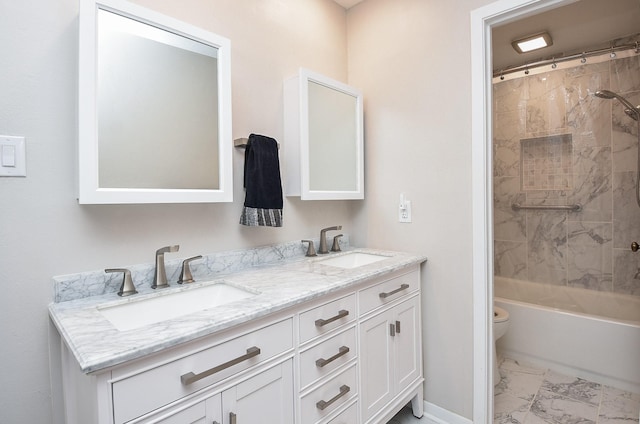 bathroom featuring double vanity, marble finish floor, toilet, and a sink