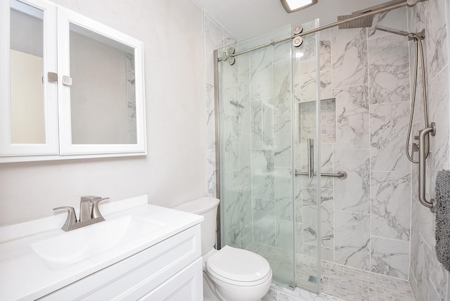 bathroom featuring toilet, a marble finish shower, and vanity