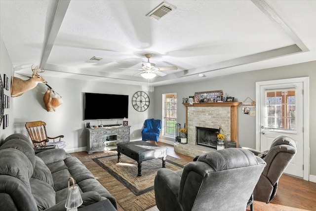 living room featuring a brick fireplace, plenty of natural light, hardwood / wood-style floors, and a textured ceiling