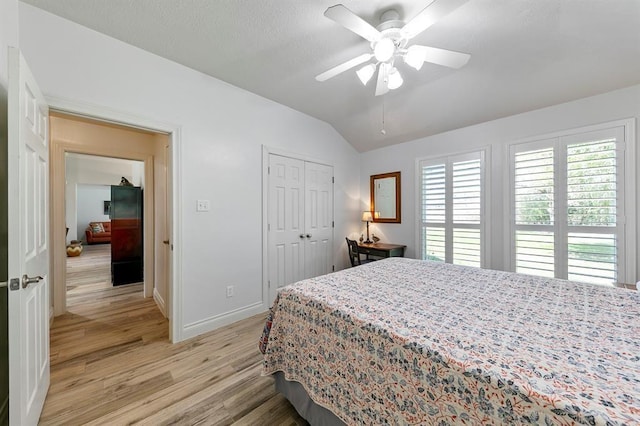 bedroom featuring light hardwood / wood-style flooring, vaulted ceiling, a closet, and ceiling fan