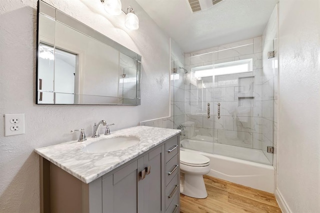 full bathroom featuring tiled shower / bath combo, vanity, hardwood / wood-style floors, and toilet