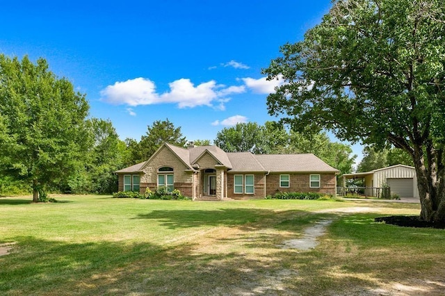 single story home featuring an outbuilding, a garage, a front yard, and a carport