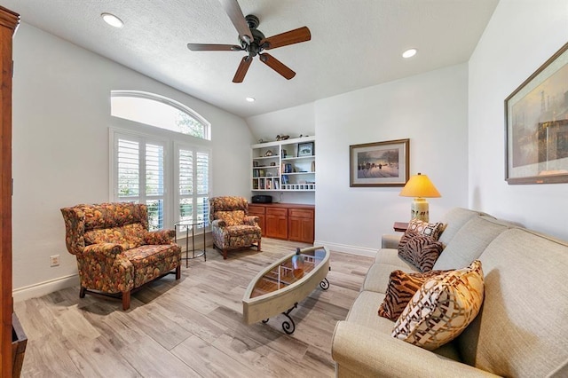 living room with ceiling fan, light hardwood / wood-style flooring, a textured ceiling, and vaulted ceiling