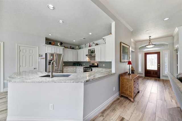 kitchen with sink, light stone counters, appliances with stainless steel finishes, kitchen peninsula, and white cabinets