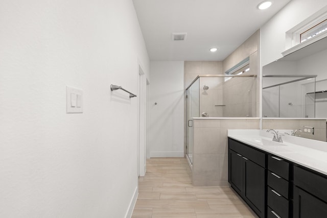 bathroom with vanity and a shower with door