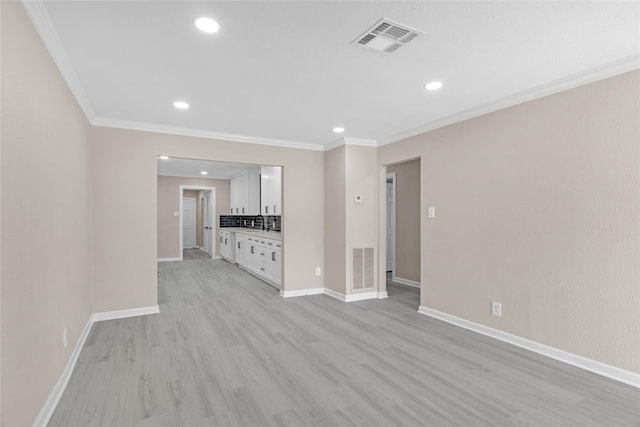 unfurnished living room with sink, ornamental molding, and light wood-type flooring